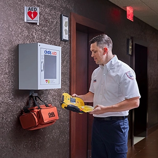 The Cintas First Aid Services employee checks on a LifeLine AED product at a customer's AED wall cabinet.